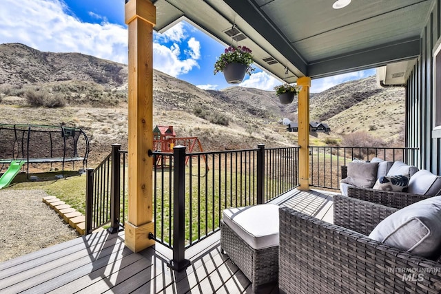 44 Shoemaker Dr, Horseshoe Bend, ID 83629 - wooden terrace featuring a playground, a trampoline, a mountain view, outdoor lounge area, and an AC wall unit