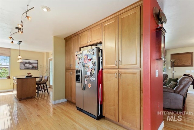 kitchen with track lighting, stainless steel refrigerator with ice dispenser, pendant lighting, and light wood-type flooring