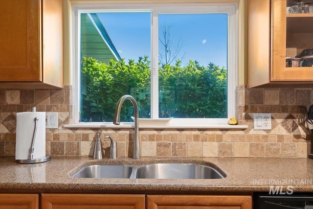 kitchen featuring light stone countertops, sink, and tasteful backsplash