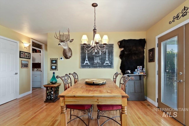 dining room featuring light hardwood / wood-style flooring, washer / dryer, and a chandelier