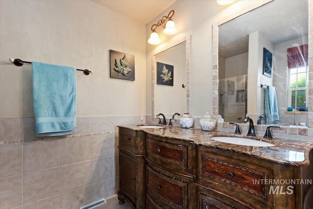 bathroom featuring tile walls and dual bowl vanity