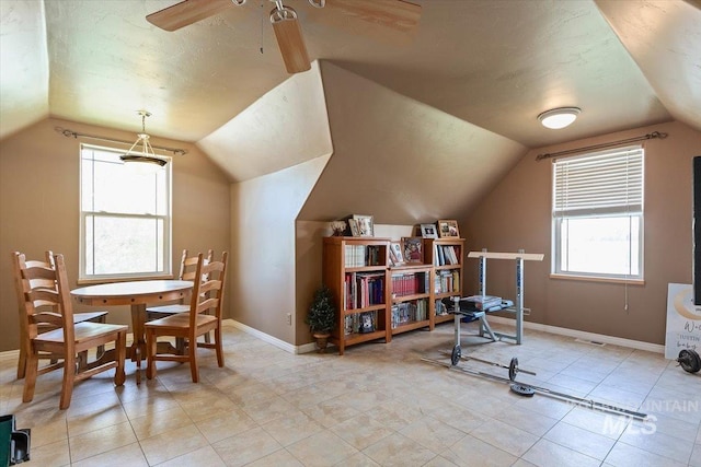 interior space with ceiling fan, lofted ceiling, and light tile floors