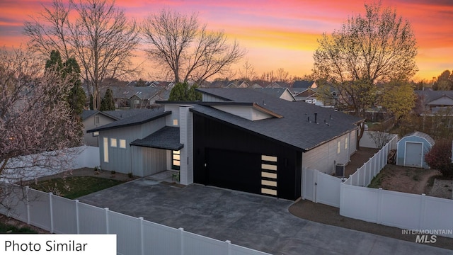 view of front facade with a shed, driveway, an outdoor structure, and a fenced backyard