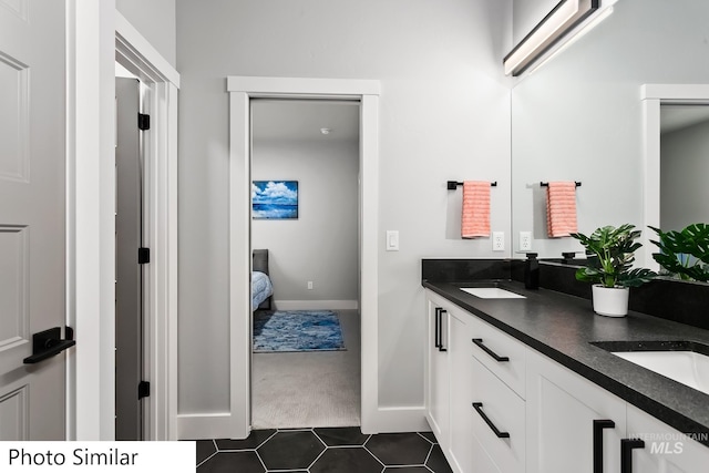 bathroom with double vanity, baseboards, tile patterned floors, and a sink