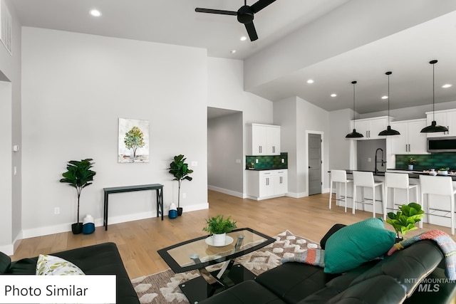 living room featuring baseboards, recessed lighting, a ceiling fan, and light wood-style floors