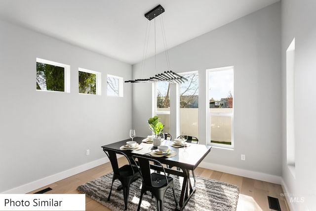 dining room featuring light wood finished floors, lofted ceiling, and baseboards