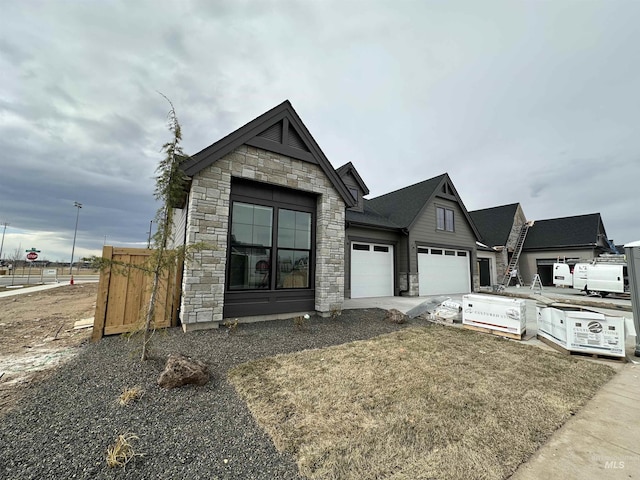 view of front of property with a garage, stone siding, and concrete driveway