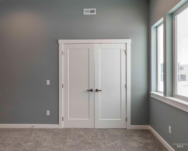 unfurnished bedroom featuring a closet, carpet flooring, visible vents, and baseboards