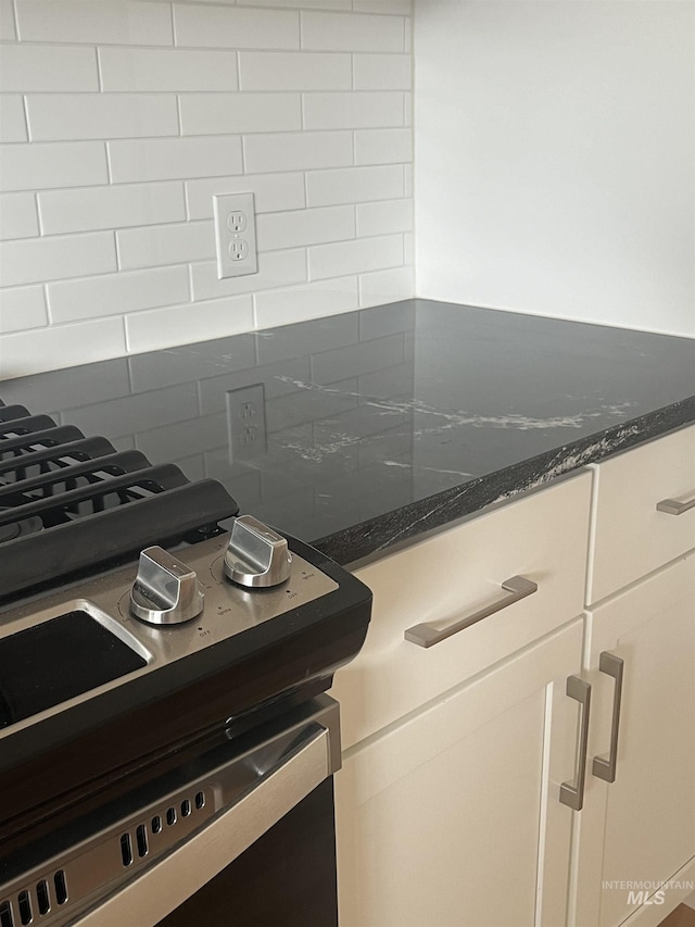 kitchen with dark stone countertops, backsplash, and white cabinets