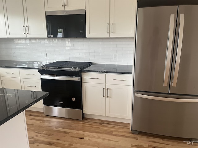 kitchen featuring light wood-type flooring, range with gas cooktop, white cabinets, and freestanding refrigerator