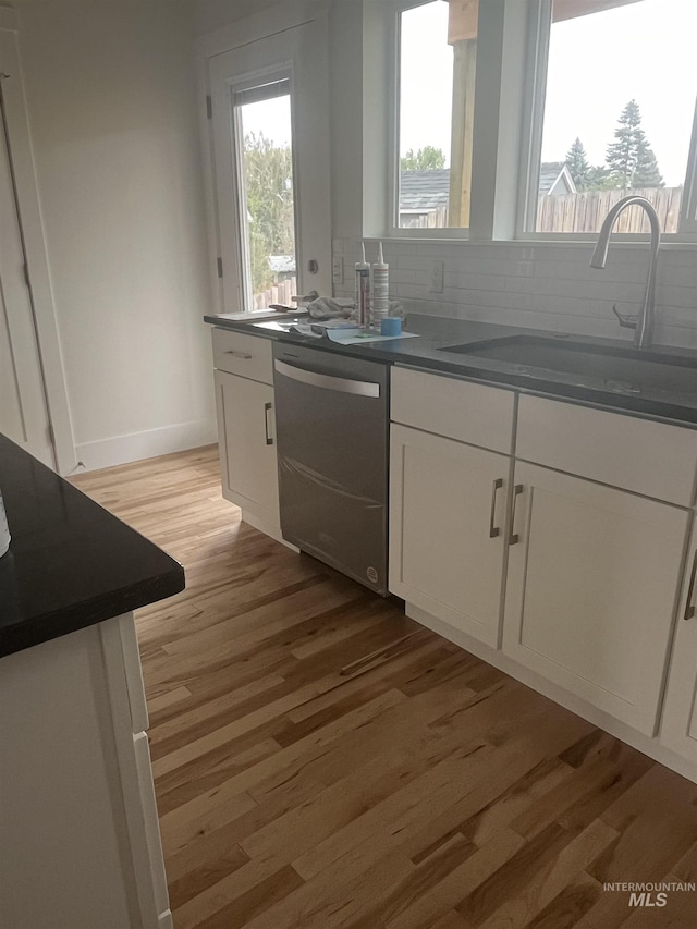 kitchen featuring dark countertops, dishwasher, and a sink