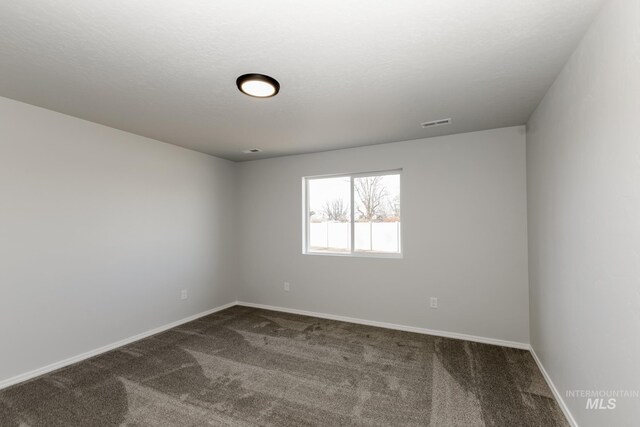 spare room with carpet flooring, baseboards, and visible vents
