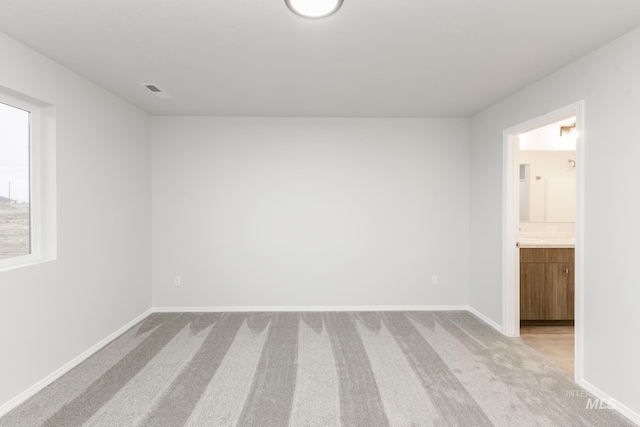 spare room with light carpet, visible vents, and baseboards