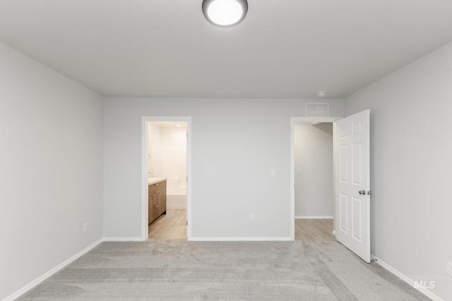unfurnished bedroom featuring connected bathroom, light colored carpet, visible vents, and baseboards