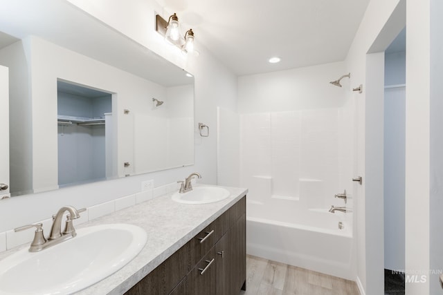 full bath featuring double vanity, a spacious closet, shower / bathtub combination, and a sink