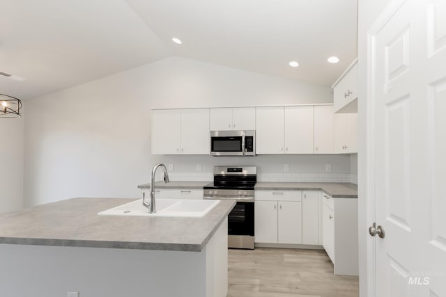 kitchen with white cabinetry, appliances with stainless steel finishes, vaulted ceiling, and a sink