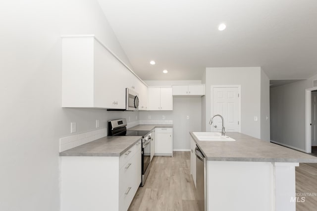 kitchen featuring a center island with sink, light wood-type flooring, stainless steel appliances, white cabinetry, and a sink
