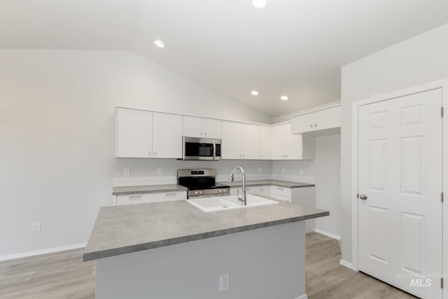 kitchen with vaulted ceiling, white cabinets, appliances with stainless steel finishes, and a sink