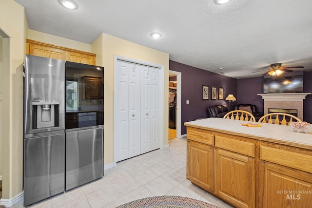 kitchen featuring stainless steel refrigerator with ice dispenser, a textured ceiling, ceiling fan, and light tile patterned flooring