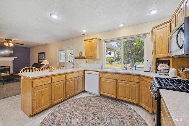 kitchen featuring sink, ceiling fan, a textured ceiling, kitchen peninsula, and stainless steel appliances