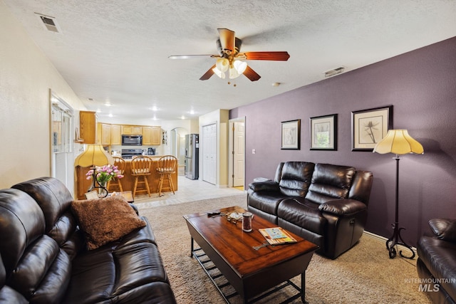 living room with ceiling fan, light colored carpet, and a textured ceiling