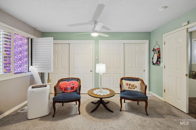 living area with ceiling fan and carpet floors