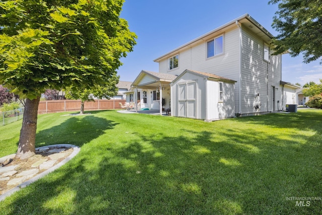 rear view of property with a lawn, a storage unit, and cooling unit