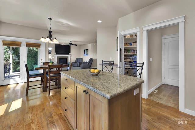 3031 N Christian Way, Meridian, ID 83646 - kitchen featuring a chandelier, a kitchen island, a fireplace, decorative light fixtures, and light stone counters