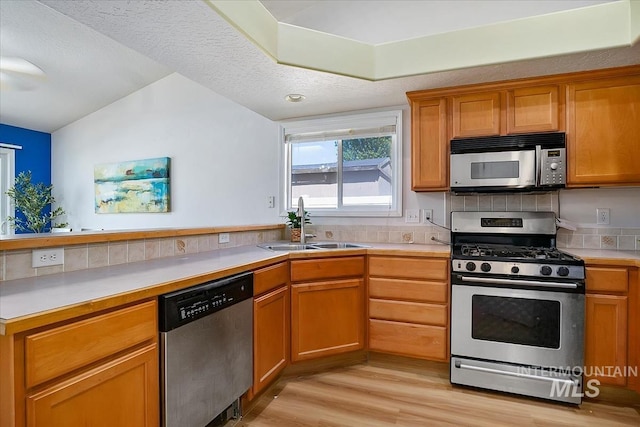 2888 W Wilder St, Meridian, ID 83642 - kitchen featuring appliances with stainless steel finishes, light wood-style floors, light countertops, vaulted ceiling, and brown cabinets