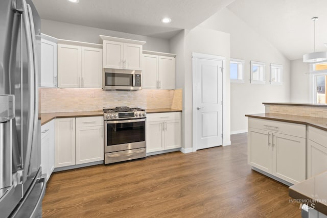 kitchen with lofted ceiling, white cabinetry, appliances with stainless steel finishes, pendant lighting, and hardwood / wood-style floors