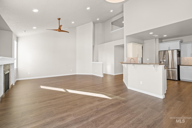 unfurnished living room featuring wood-type flooring, high vaulted ceiling, and ceiling fan