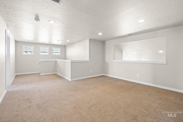 carpeted empty room with a textured ceiling