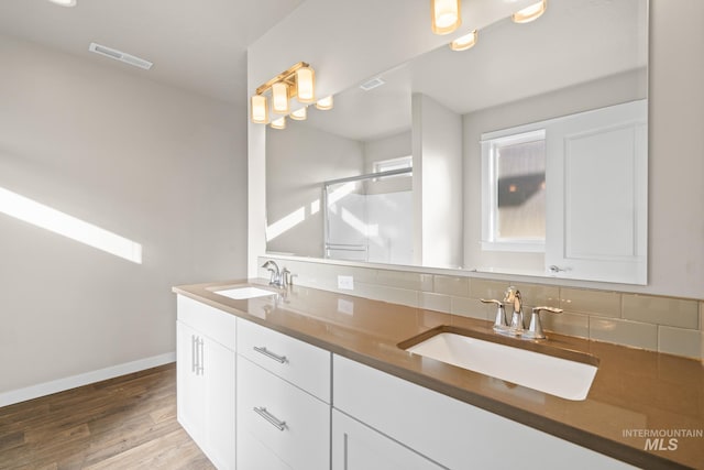 bathroom featuring hardwood / wood-style flooring, vanity, tasteful backsplash, and a shower with shower door