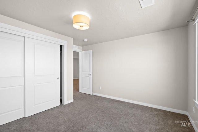 unfurnished bedroom featuring dark colored carpet and a closet