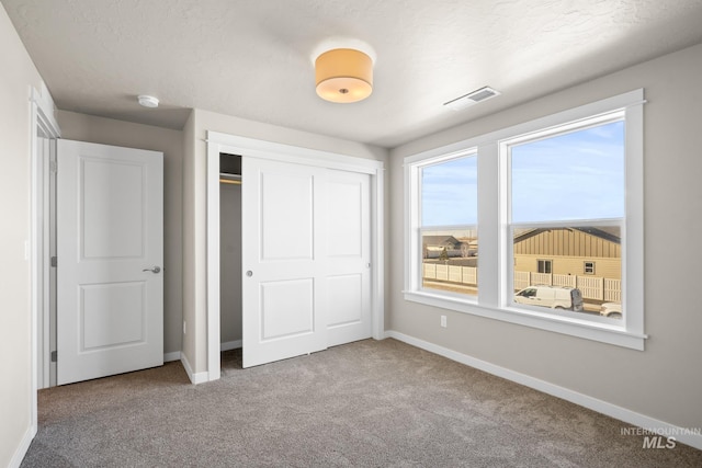 unfurnished bedroom with a closet, carpet, and a textured ceiling