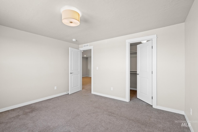 unfurnished bedroom featuring a walk in closet, carpet floors, and a closet