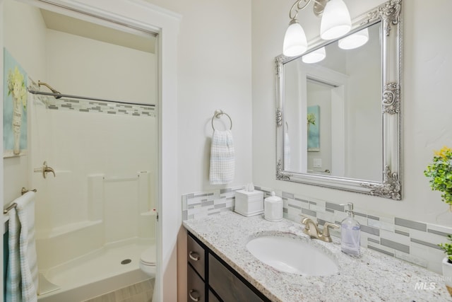 12371 S Abbott Downing Way, Nampa, ID 83686 - bathroom featuring a walk in shower, tasteful backsplash, vanity, and toilet