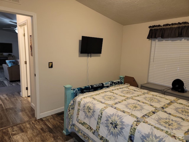 bedroom featuring lofted ceiling, dark hardwood / wood-style flooring, and a textured ceiling