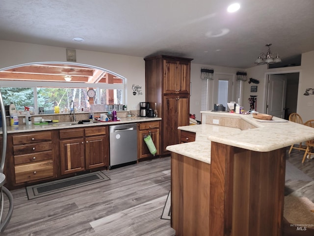 kitchen featuring dishwasher, sink, an inviting chandelier, a breakfast bar, and light wood-type flooring