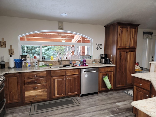 kitchen with hardwood / wood-style flooring, sink, light stone countertops, and appliances with stainless steel finishes