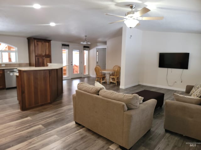 living room featuring ceiling fan with notable chandelier, dark hardwood / wood-style flooring, and vaulted ceiling