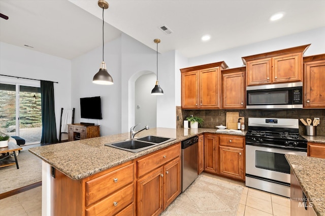 kitchen with light stone countertops, appliances with stainless steel finishes, tasteful backsplash, sink, and decorative light fixtures