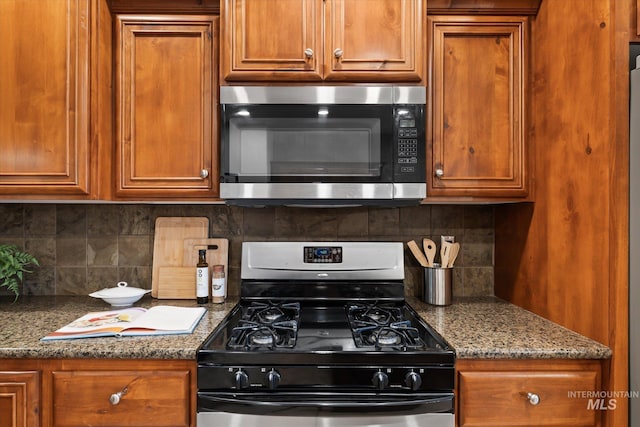 kitchen featuring decorative backsplash, dark stone counters, and appliances with stainless steel finishes