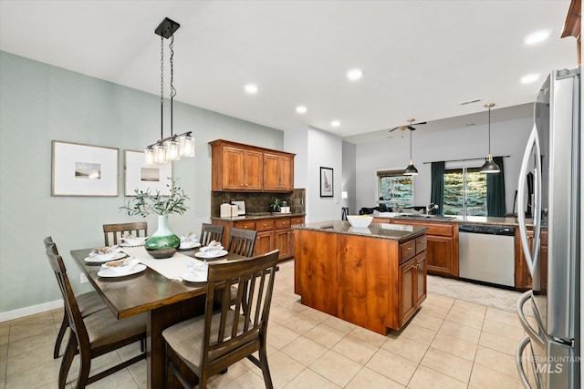 kitchen with light tile patterned floors, a kitchen island, decorative light fixtures, and appliances with stainless steel finishes