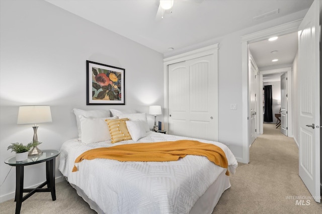 bedroom featuring light colored carpet, a closet, and ceiling fan