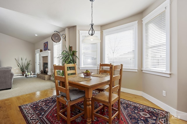 dining area with plenty of natural light, baseboards, vaulted ceiling, and a glass covered fireplace