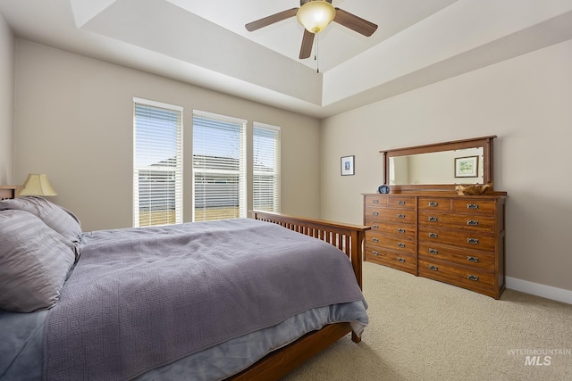 bedroom featuring ceiling fan, a tray ceiling, carpet, and baseboards