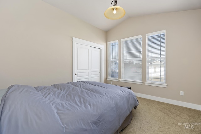 bedroom featuring a closet, baseboards, vaulted ceiling, and carpet flooring