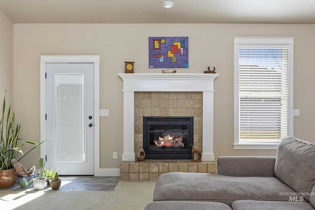 living area featuring a healthy amount of sunlight, baseboards, and a tiled fireplace