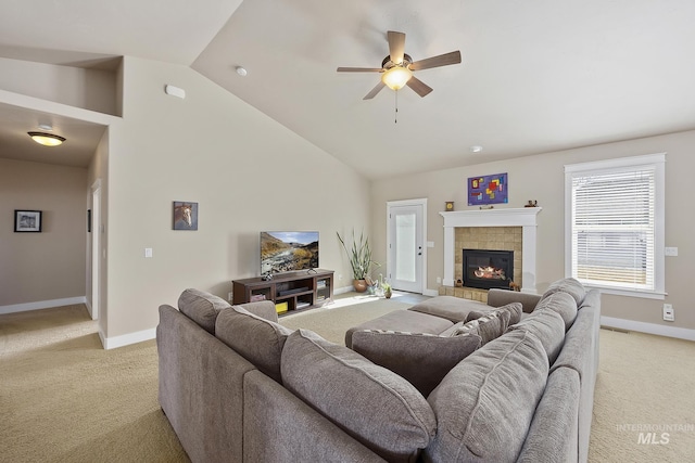 living room with ceiling fan, high vaulted ceiling, a tile fireplace, and light colored carpet